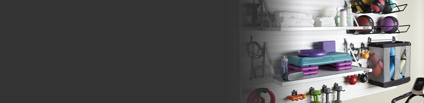 Un mur de garage avec une tablette contenant de l’équipement d’entraînement et une autre avec des serviettes pliées. Sur le mur, on voit différents articles comme des haltères et des ballons de basketball sont accrochés à l’aide de crochets muraux Gladiator