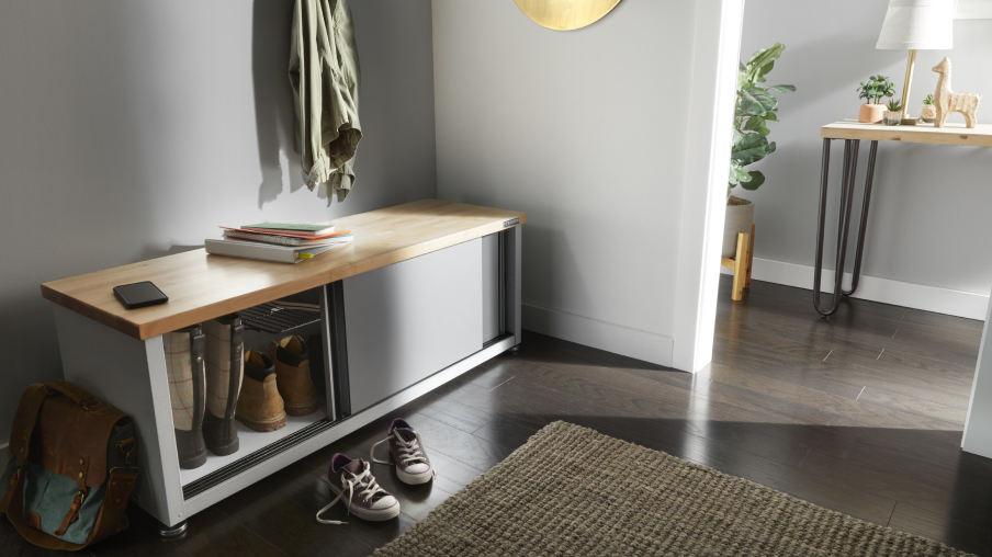  In a room is a Gladiator shoe rack. Its panel door is open, revealing a couple of pairs of boots.
