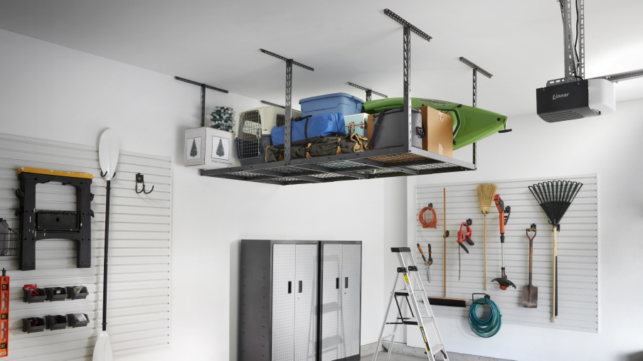 Dans un système de rangement suspendu Gladiator, des bacs et des articles sont rangés au-dessus du sol. À côté, deux unités de rangement Gladiator se trouvent près d’un mur où un balai, un râteau, une pelle et d’autres articles sont accrochés à des crochets muraux Gladiator.