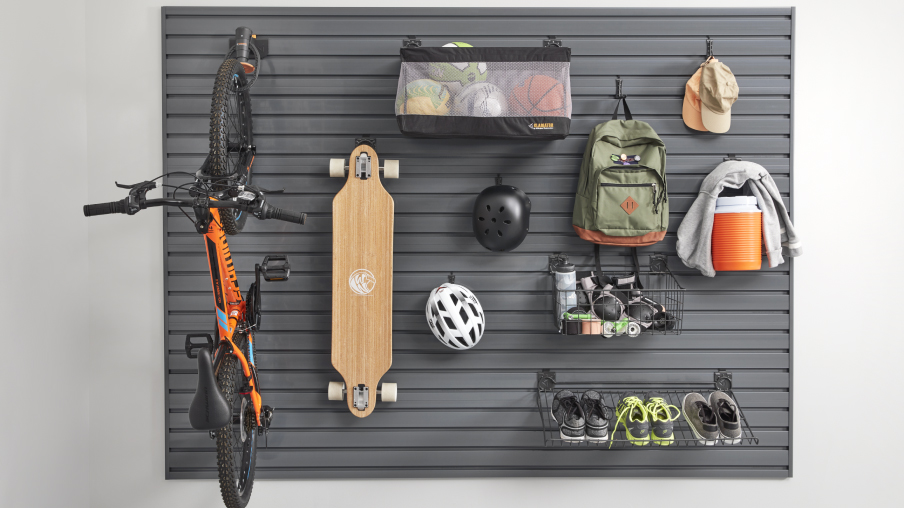 Un vélo, une planche à roulettes, des casques, un sac à dos, des chapeaux et des chaussures sont accrochés à des crochets muraux Gladiator et à un support.