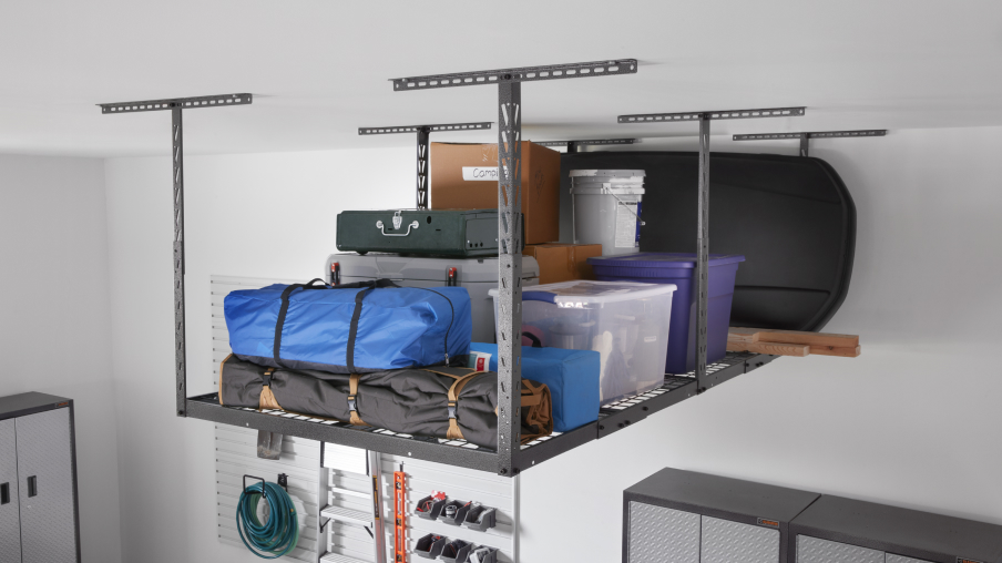 Dans un garage, des articles, dont des boîtes et des bacs, sont rangés dans un système de rangement suspendu Gladiator.