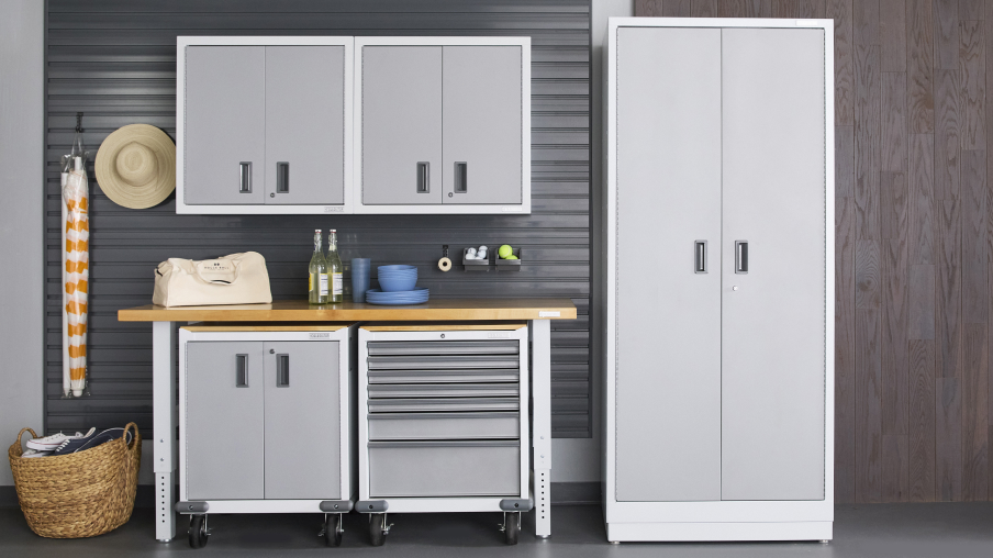 Un garage organisé à l’aide d’armoires et d’unités de rangement Gladiator. Un chapeau est suspendu au mur et un panier en osier se trouve au sol. Sous deux armoires Gladiator, un établi Gladiator sur lequel se trouvent quelques articles, dont des bouteilles de vin. Au-dessus de l’établi, deux bacs Gladiator.