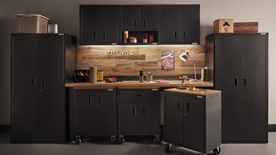 Un garage bien rangé avec un mur de solutions de rangement Gladiator, comme des armoires sur roulettes et murales, ainsi que deux unités de rangement. Quelques articles, dont un rouleau d’essuie-tout, se trouvent sur l’établi.