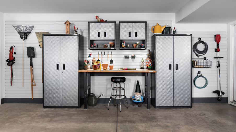 Un garage organisé avec des systèmes de rangement Gladiator. On y trouve deux unités de rangement Gladiator reliées par un établi et deux armoires Gladiator. De l’équipement de jardinage est suspendu au mur à l’aide de crochets Gladiator.