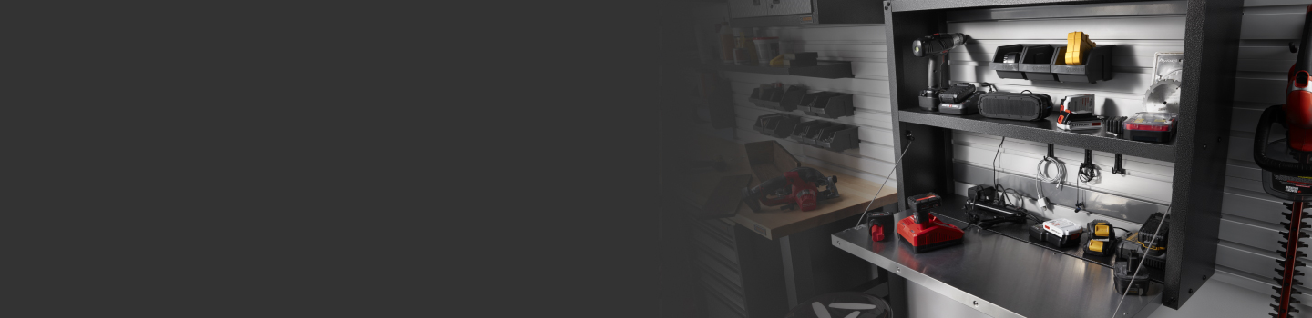 Sur une étagère dans un garage se trouvent divers outils électriques. Sur les murs sont accrochés des outils de jardinage et des paniers Gladiator