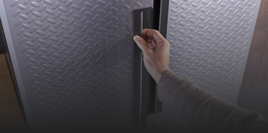 A hand holds the handle of a Gladiator Cabinet door