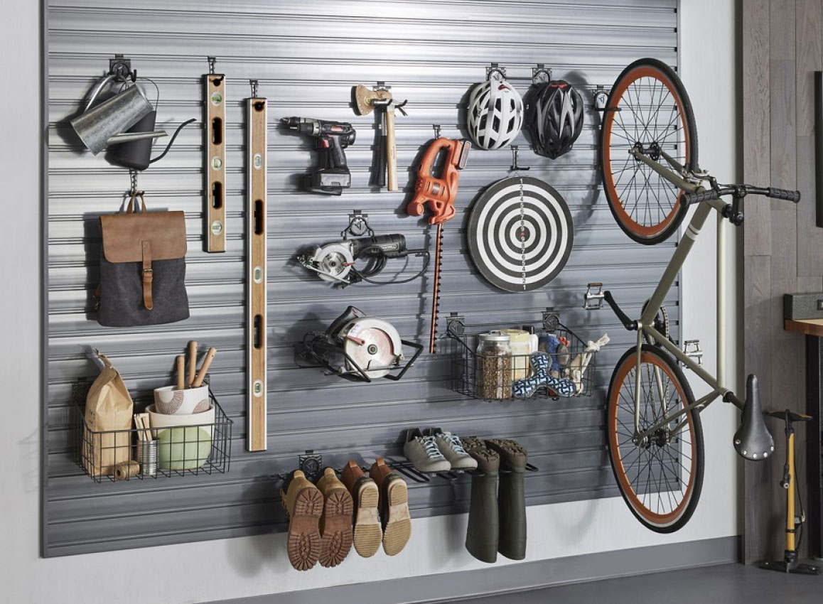 Un vélo, des niveaux, des bottes, un sac, des casques de vélo et autres objets sont organisés sur un mur avec les solutions de rangement Gladiator