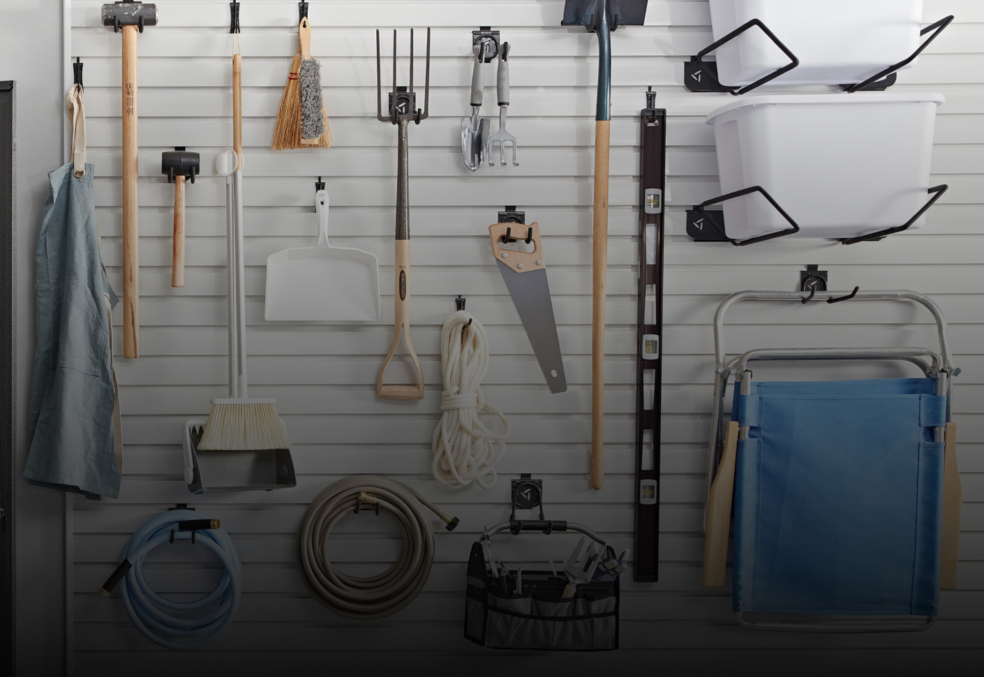 A man reads a manual at a Gladiator Workbench next to a full pencil holder. Gladiator Cabinets are behind him on the wall and there's a Gladiator Mobile Tool Storage Chest. Tools and automatic tools are along the workbench in the background and various items hang on Gladiator Hooks and in Gladiator Bins