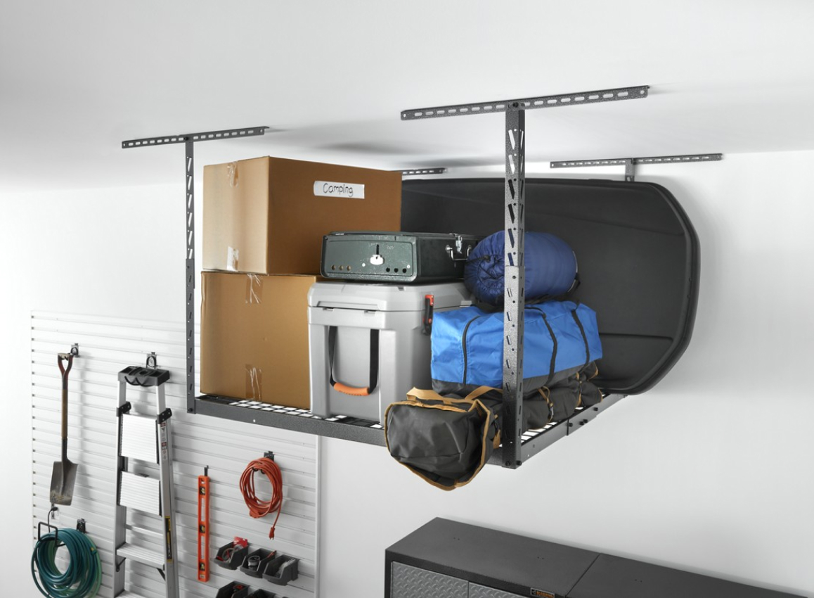 A Gladiator Overhead Storage with various items: two boxes, bins, a case, three bags with camping equipment like a sleeping bag and a black board