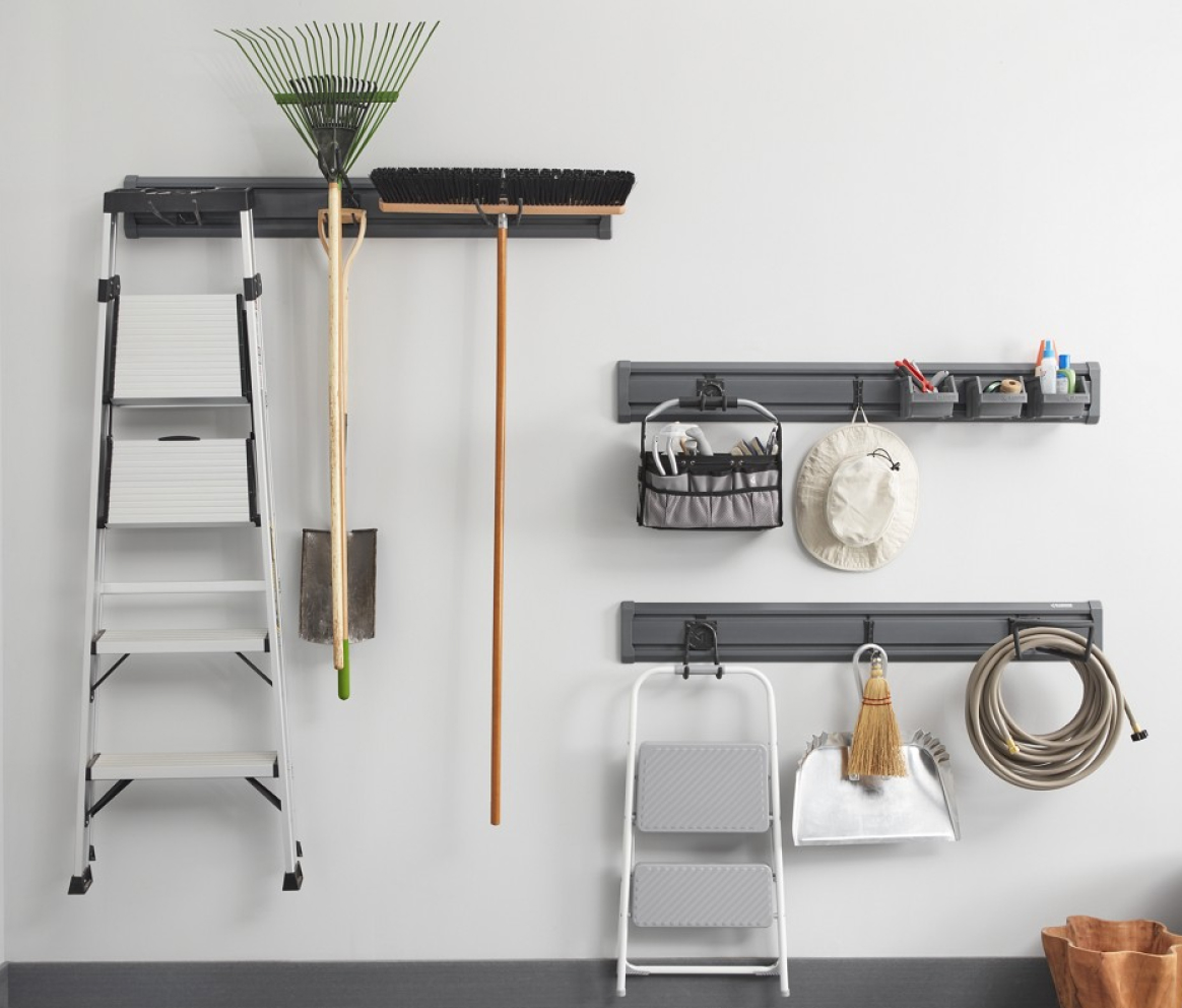 Hanging on three Gladiator Wall Systems are a ladder, rake, broom, hat, items in baskets, step stool, broom and dust pan and garden hose