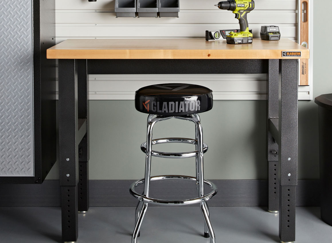A Gladiator Workbench with a drill on top. There's a stool and Gladiator Bins on the wall