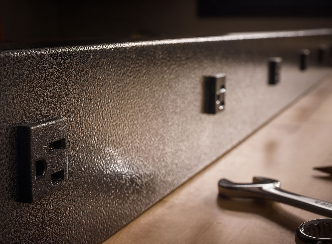 A wall lined with outlets and a wrench laying in front