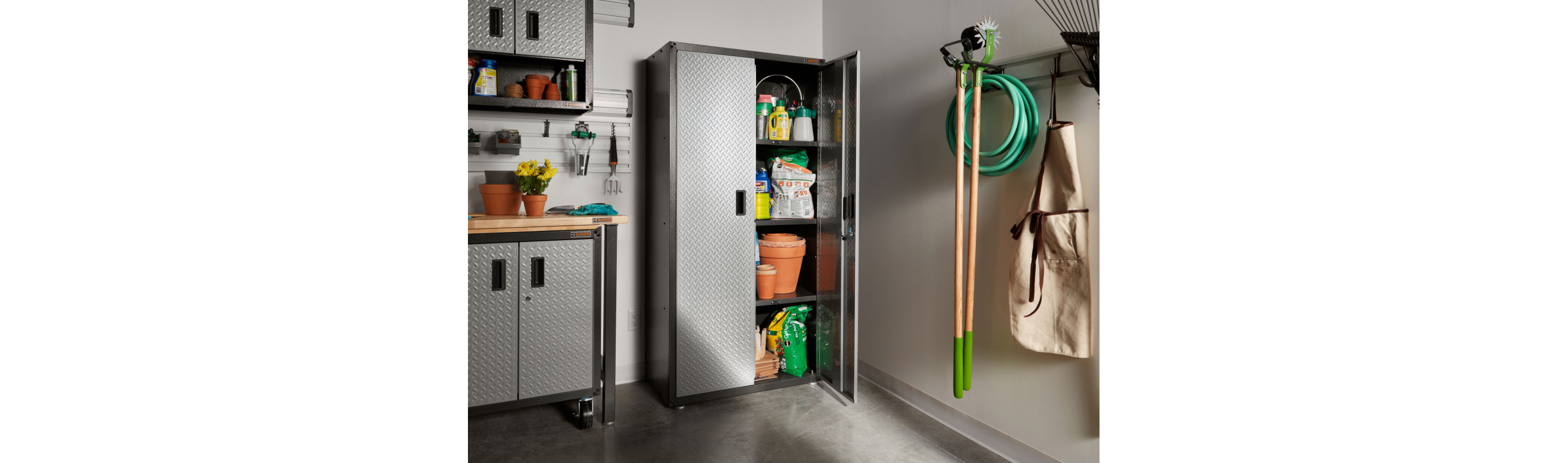 A garage with several Gladiator solutions: Gladiator Modular Cabinets and a Gladiator Full-Size Cabinet with one door open. Inside the full-size cabinet are plant pots, bags of soil and other gardening items. On the wall are an apron, a garden hose and gardening tools