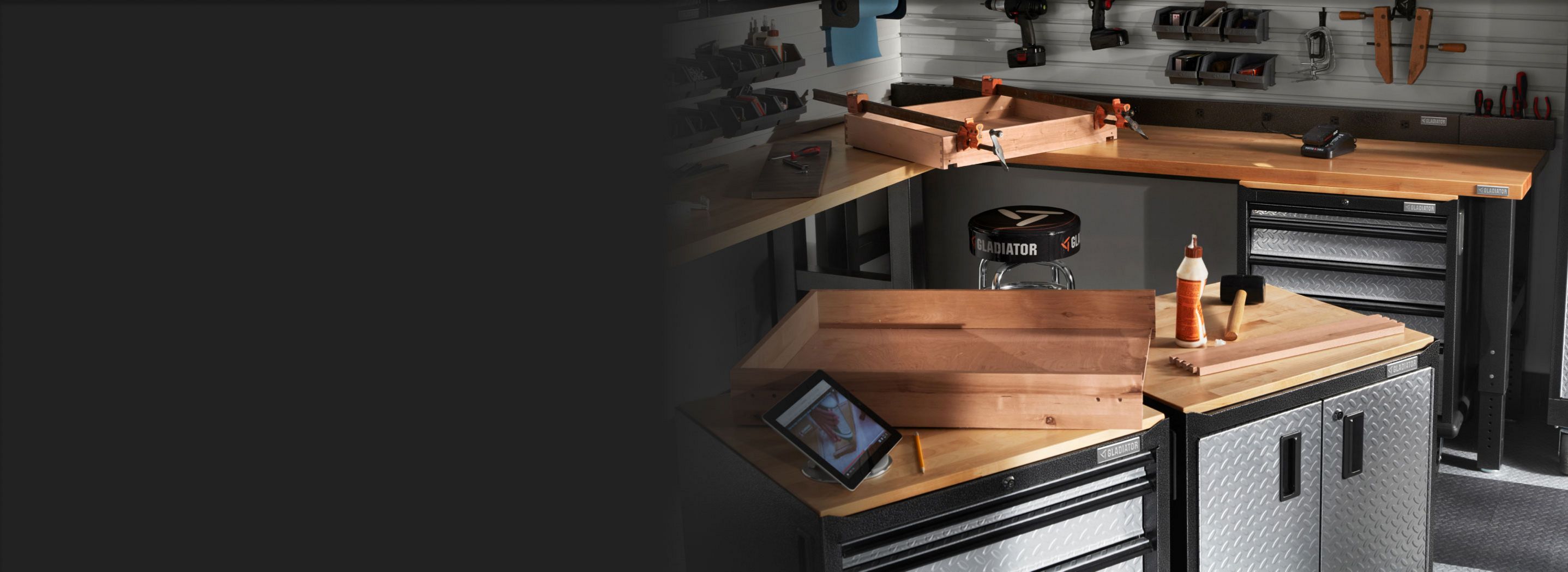 A garage with Gladiator Modular Cabinets and Gladiator Workbench. Gladiator Bins and Baskets and tools are scattered around and on the wall