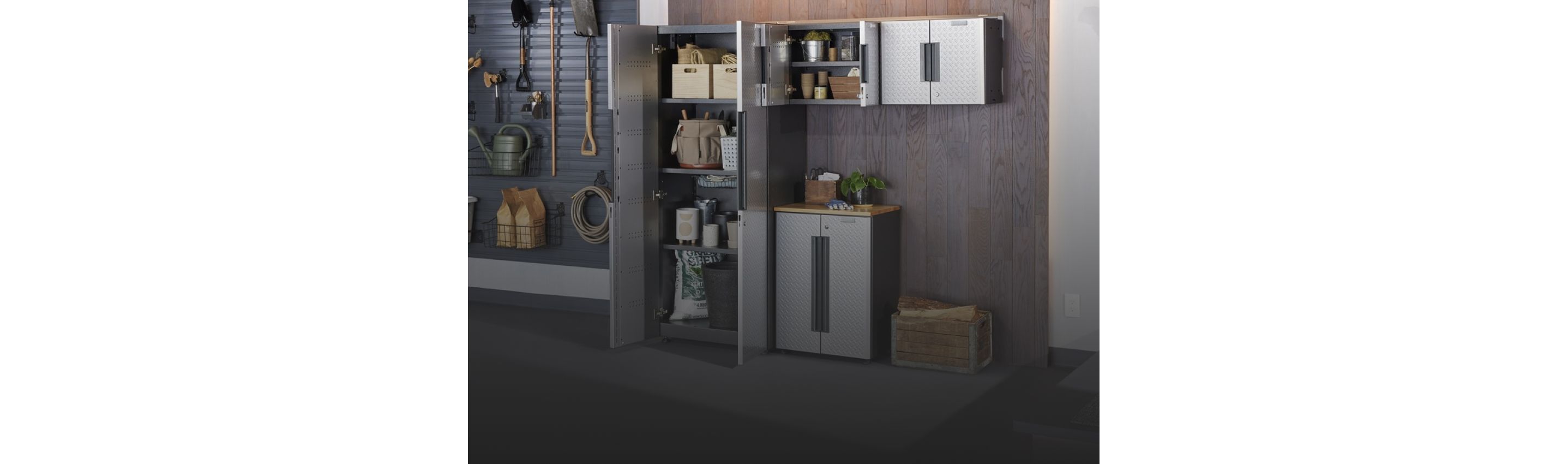 A garage with a Gladiator Flex Cabinet System. The vertical cabinet doors are opened revealing a toolbox, baskets, paint cans, a bag of soil and other various items. One of the top cabinets is also opened and on the shelves are baskets, a metal container and more