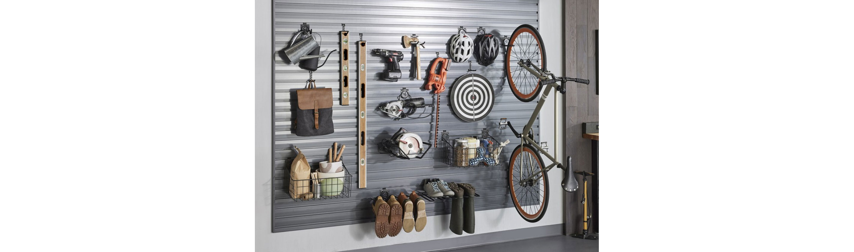 A Gladiator wall organization system with a bike, two bike helmets, two levels, a basket with items, boots, shoes and tools.
